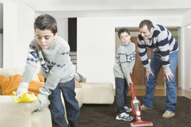 Father and two sons cleaning the living room