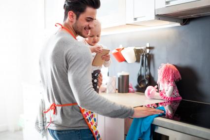 Father carrying child while cleaning the kitchen