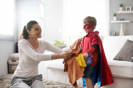 Child in superhero costume helping with laundry