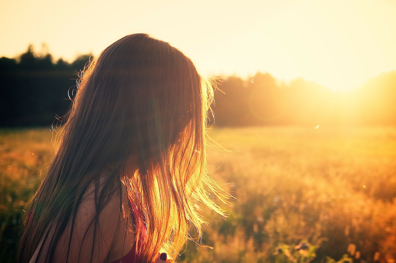 Girl walking through field in the sun